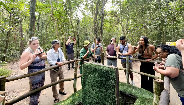 Visitors observing booby trap demonstration at Cu Chi Tunnels, Vietnam.