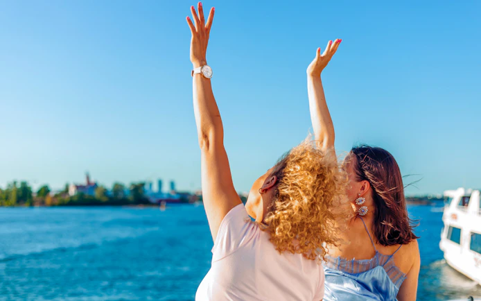 Guests enjoying the Helsinki sightseeing cruise with arms raised over the water.