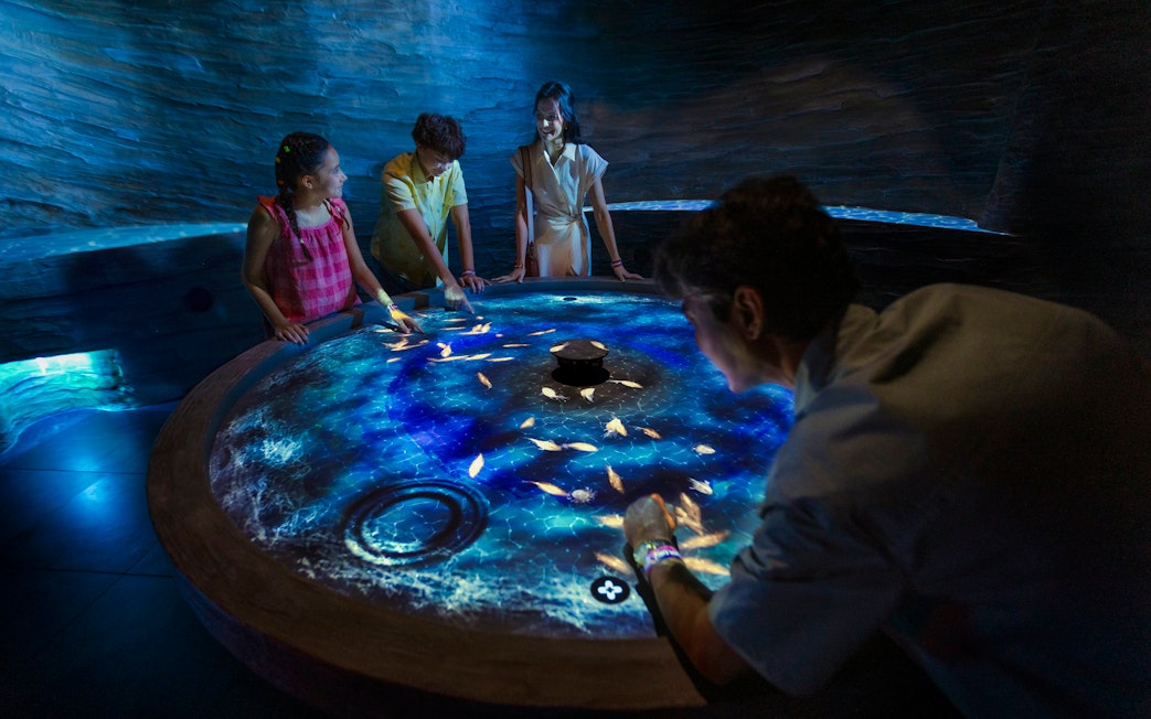 Visitors interact with digital fish at the World of Darkness table, Exploria, Mandai Wildlife.