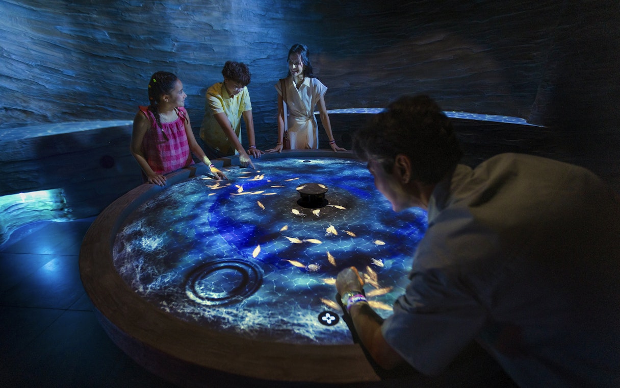 Visitors interact with digital fish at the World of Darkness table, Exploria, Mandai Wildlife.