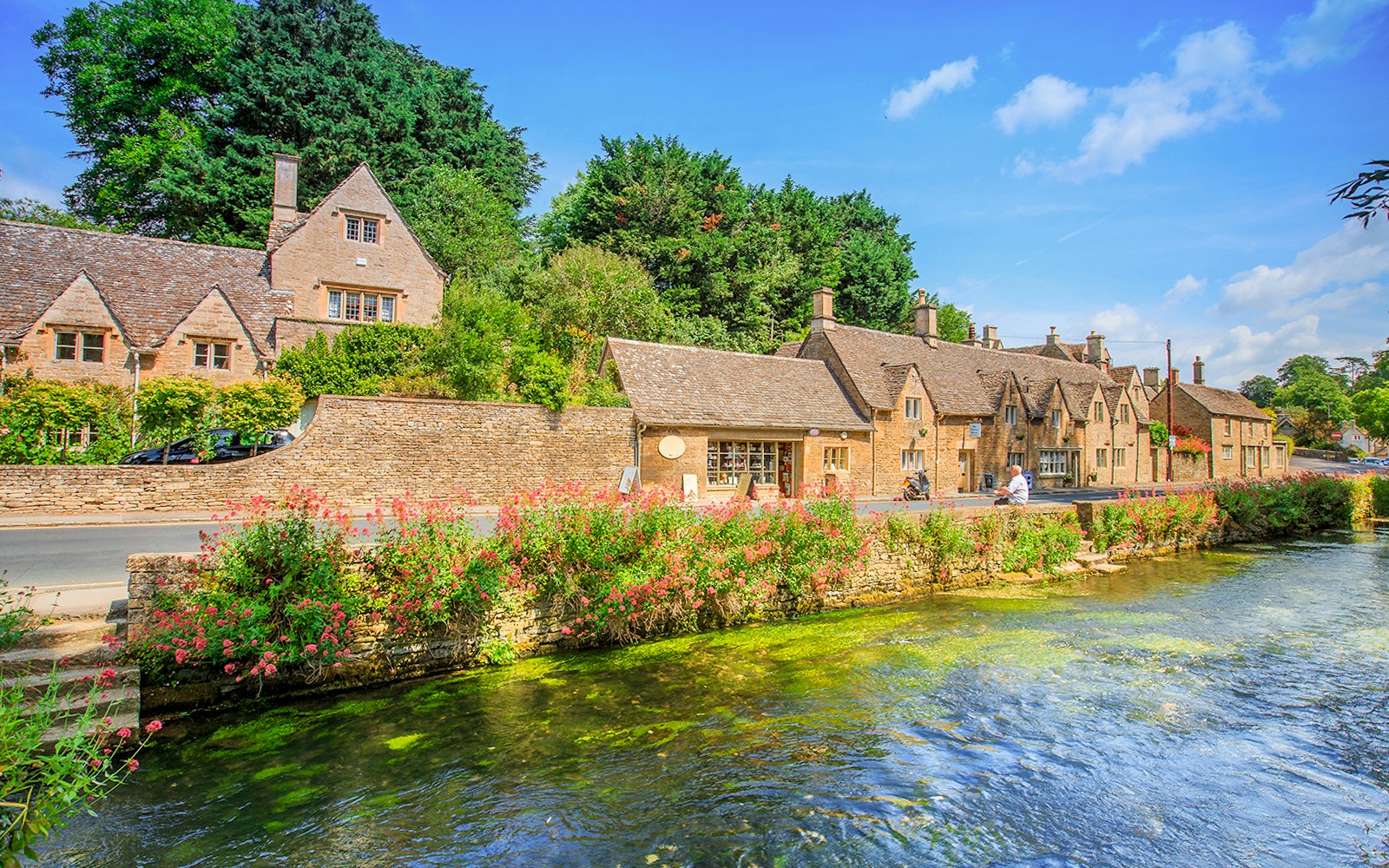 Arlington Row cottages in Bibury, England, with a river and lush greenery.
