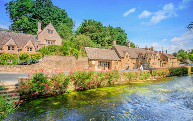 Arlington Row cottages in Bibury, England, with a river and lush greenery.