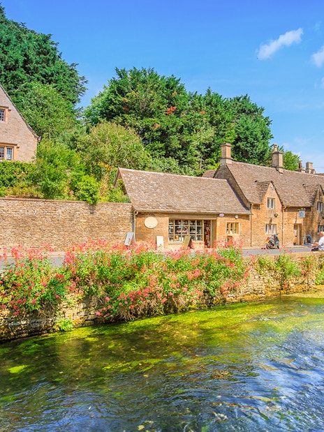 Arlington Row cottages in Bibury, England, with a river and lush greenery.
