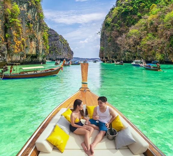 Couple enjoying a boat tour in the turquoise waters of Phi Phi Islands, Thailand.