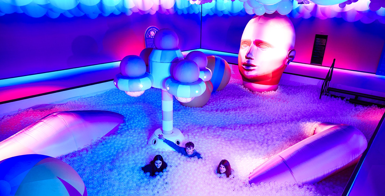 Interactive Bubble Planet exhibit with colorful inflatables and visitors in a ball pit.