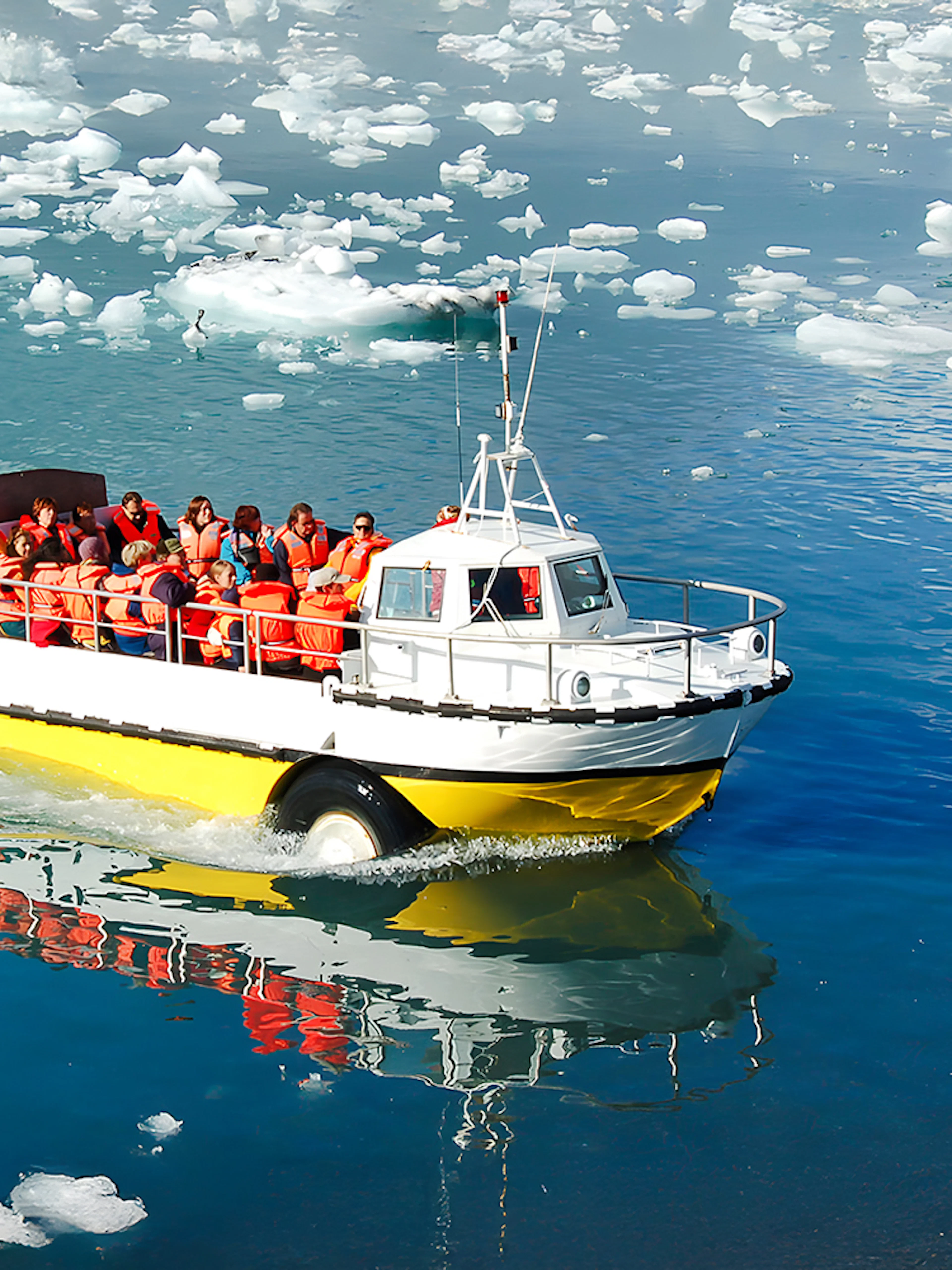Boat with tourists on Jökulsárlón Glacial Lagoon, Iceland, surrounded by icebergs.