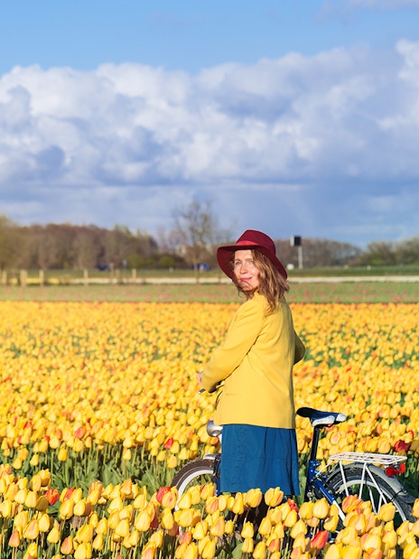 Person standing with a bicycle in a field of yellow tulips at Keukenhof, Netherlands.