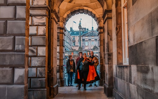 Group on guided tour under archway in Edinburgh Old Town.