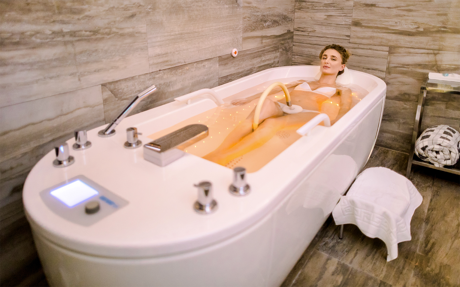 Woman receiving underwater jet massage in a spa tub, enhancing relaxation and wellness experience.
