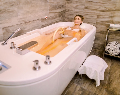 Woman receiving underwater jet massage in a spa tub, enhancing relaxation and wellness experience.