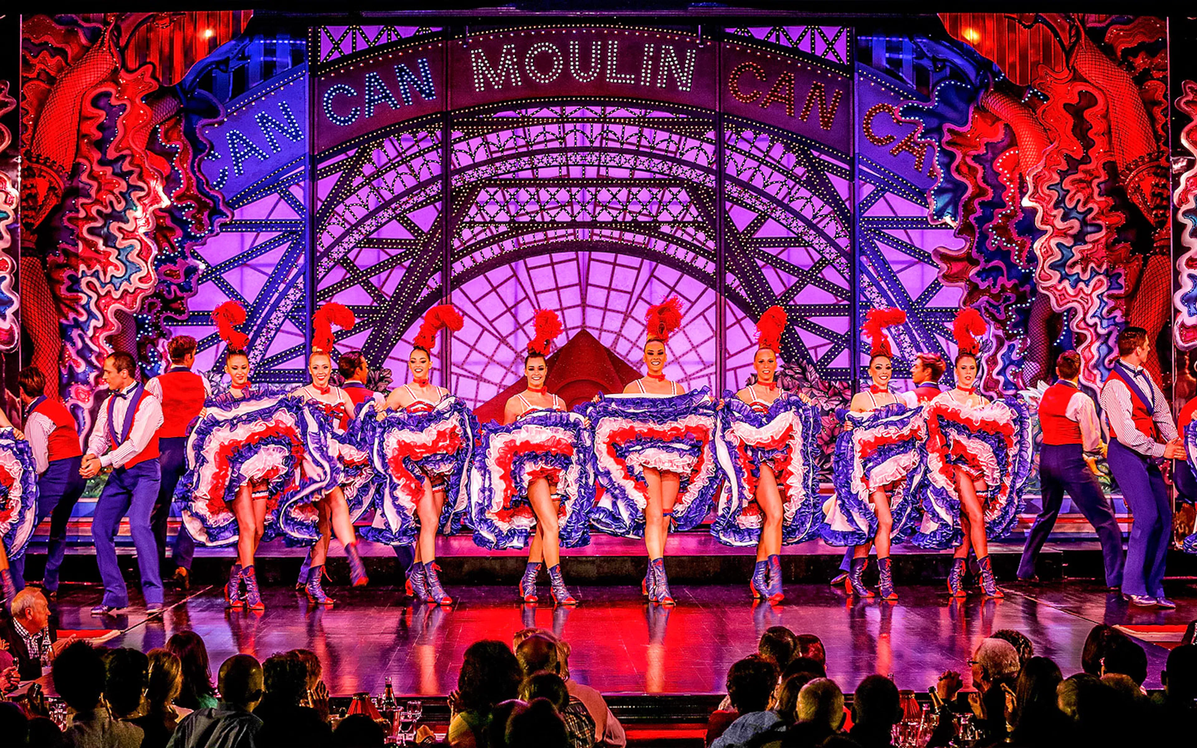 Moulin Rouge cabaret performers in vibrant costumes on stage in Paris, France.