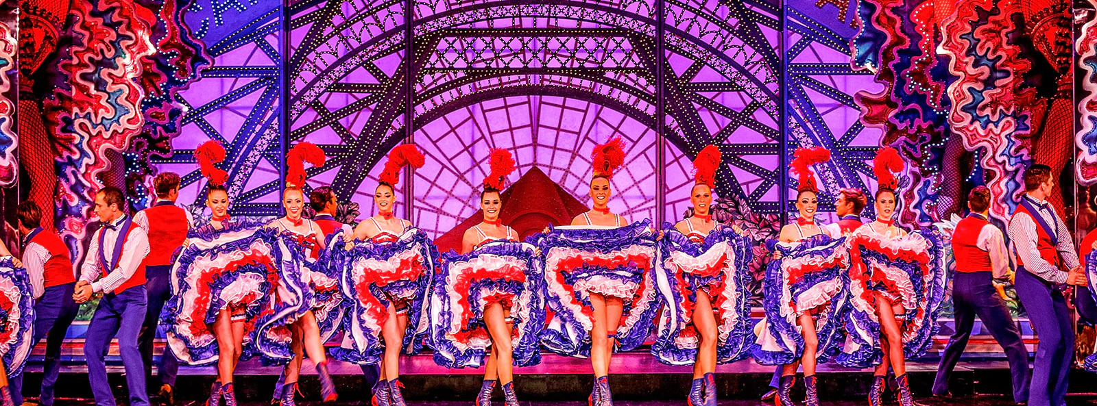 Moulin Rouge cabaret performers in vibrant costumes on stage in Paris, France.
