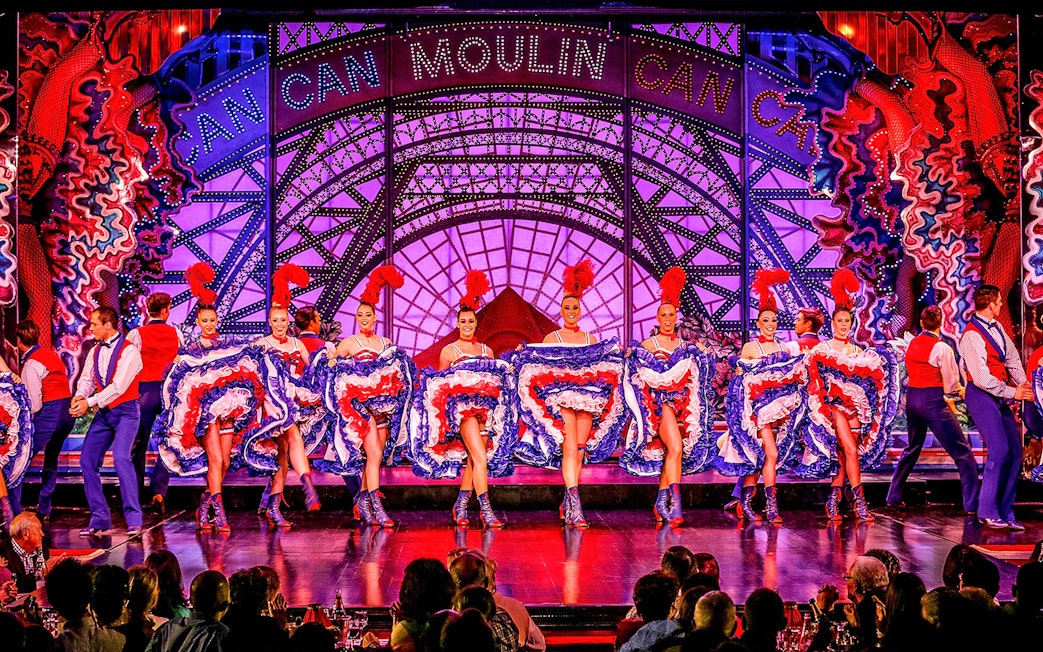 Cabaret dancers performing at Moulin Rouge in Paris with vibrant costumes.