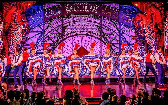 Cabaret dancers performing at Moulin Rouge in Paris with vibrant costumes.
