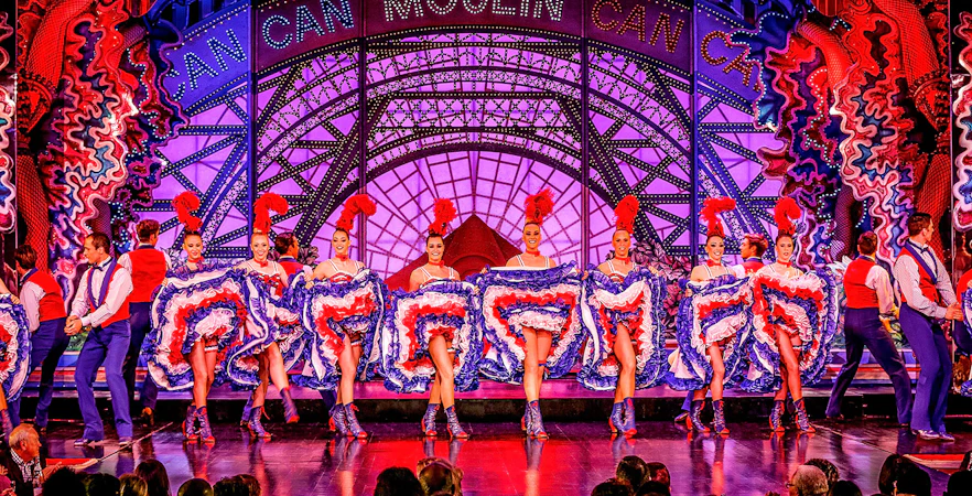 Cabaret dancers performing at Moulin Rouge in Paris with vibrant costumes.