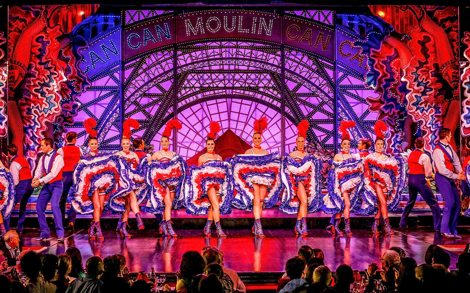 Cabaret dancers performing at Moulin Rouge in Paris with vibrant costumes.