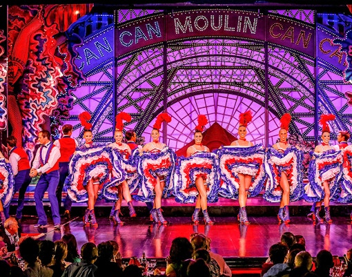 Des artistes du cabaret Moulin Rouge en costumes éclatants sur scène à Paris, en France.