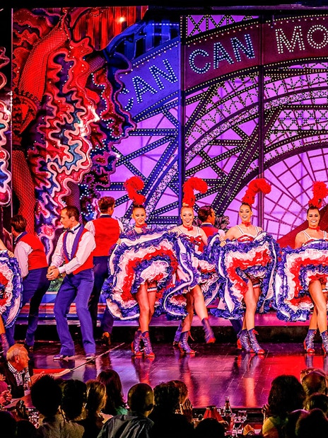 Cabaret dancers performing at Moulin Rouge in Paris with vibrant costumes.