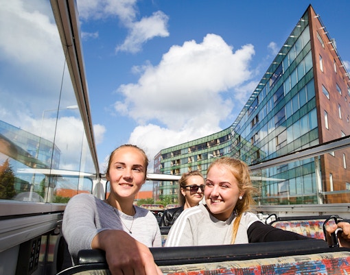 Double-decker bus on New Orleans Hop-On Hop-Off tour passing historic French Quarter buildings.