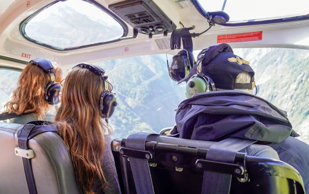 Helicopter passengers viewing scenic mountain landscape through windows.