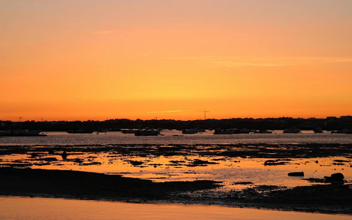 Sunset view over Ria Formosa with boats on the water.