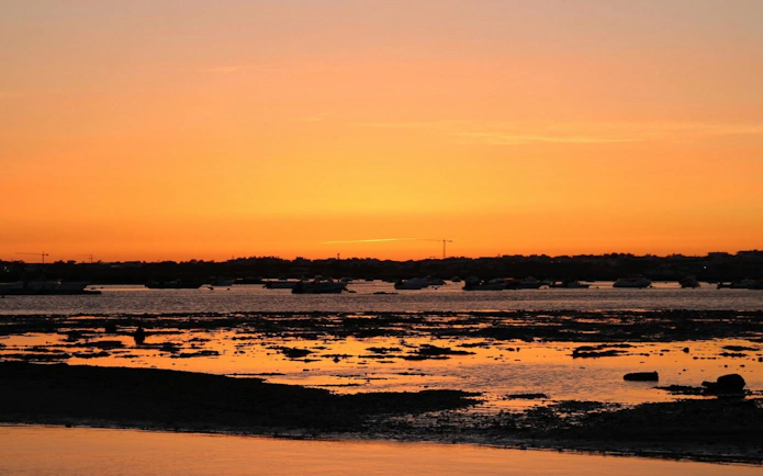 Sunset view over Ria Formosa with boats on the water.