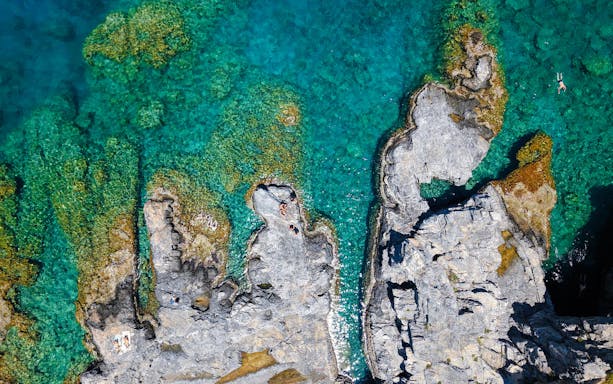 Rocky coastline with clear turquoise water, Rhodes cruise.