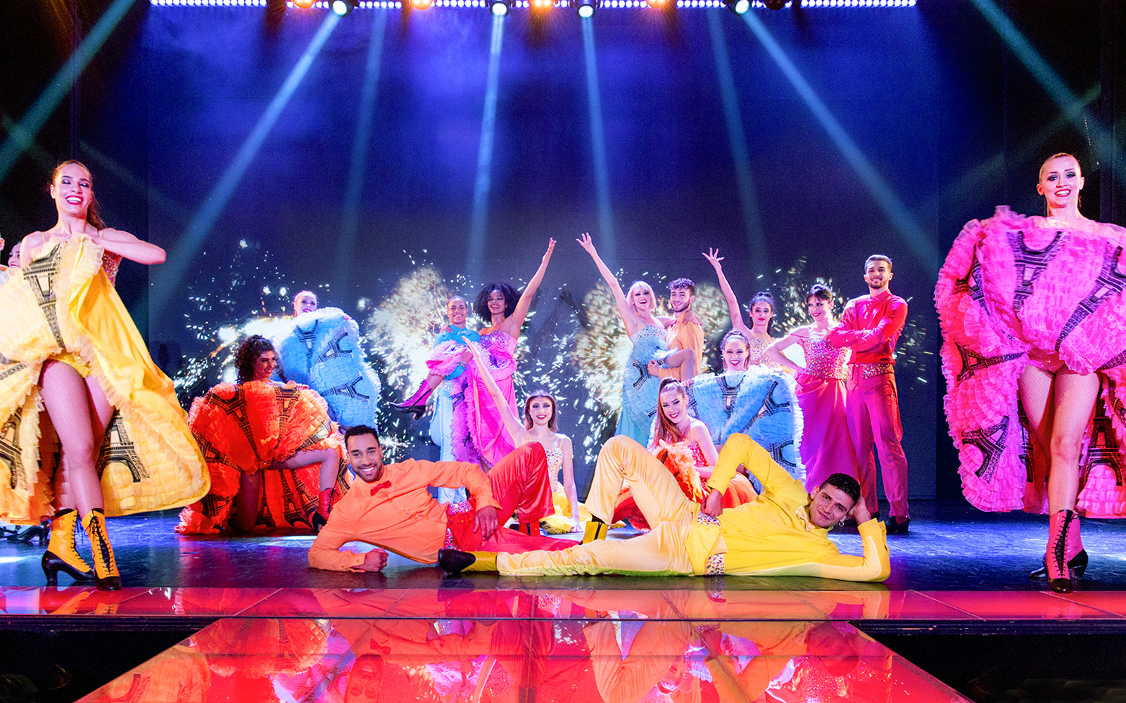 Cabaret performers in colorful costumes on stage during Paris New Year's Eve show.