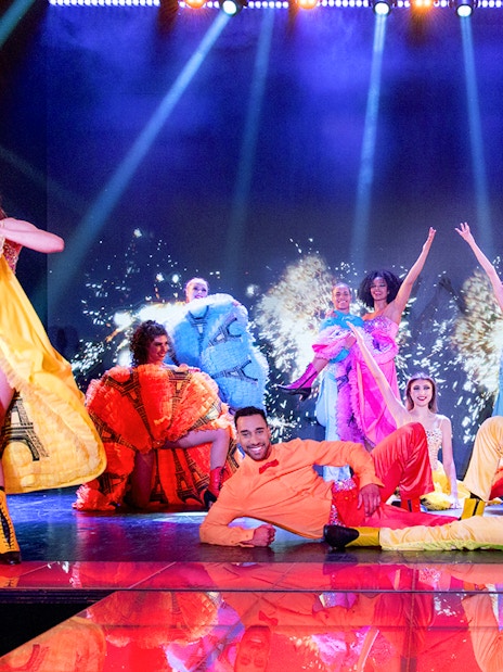 Cabaret performers in colorful costumes on stage during Paris New Year's Eve show.