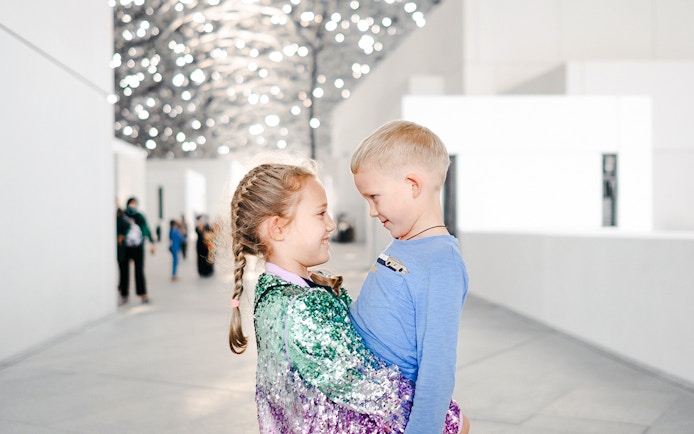 Children smiling under the Louvre Abu Dhabi's dome.