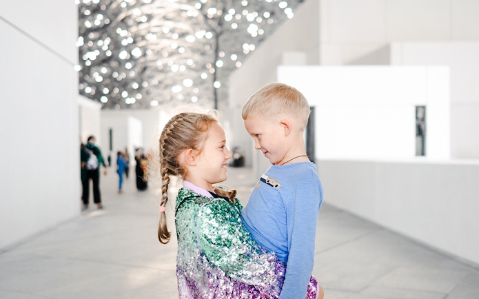 Children smiling under the Louvre Abu Dhabi's dome.
