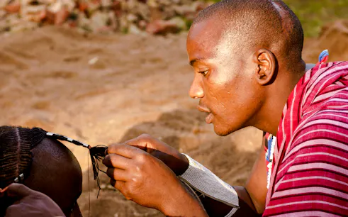 Maasai man braiding hair in a village, Zanzibar.