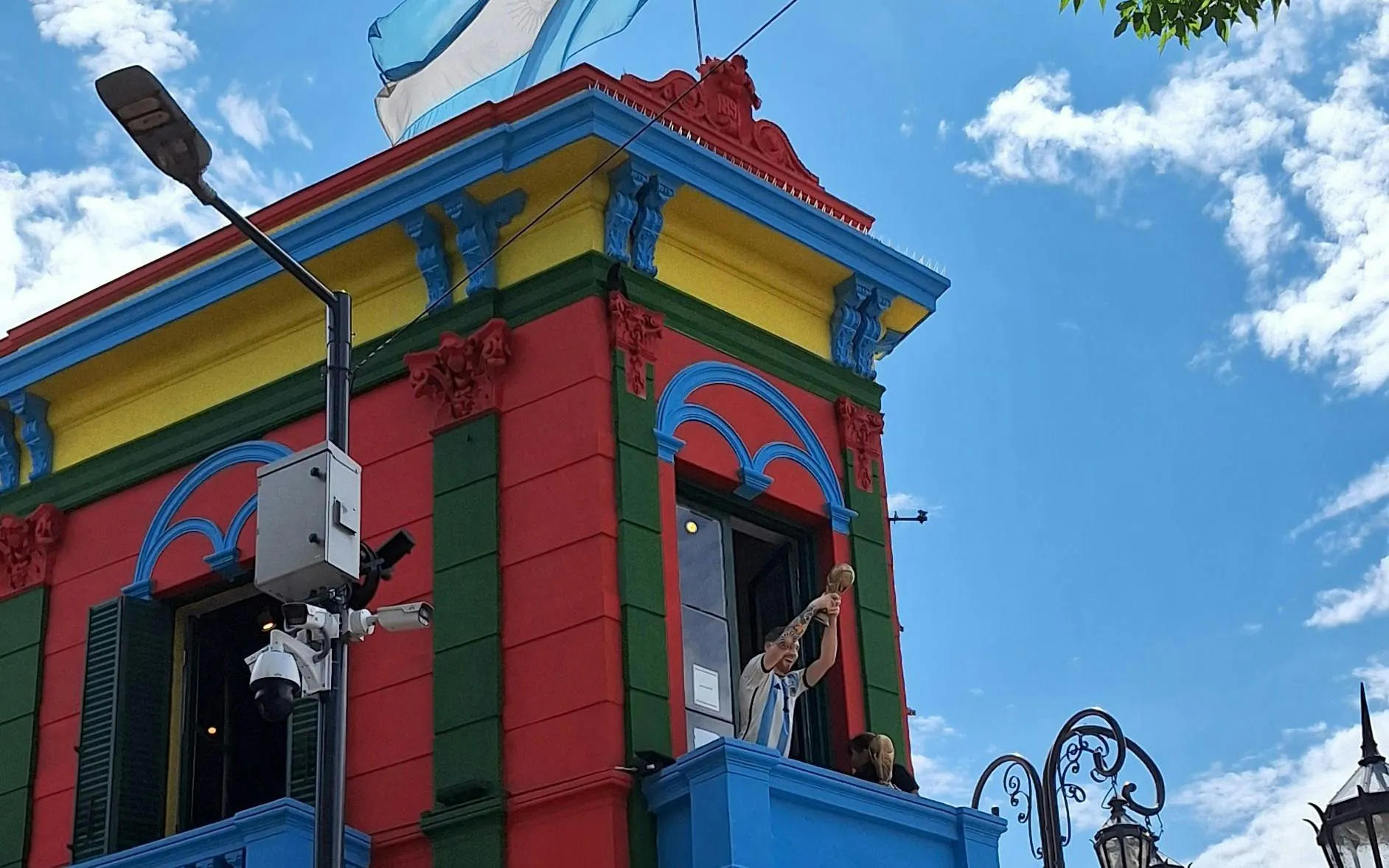 Colorful building in La Boca, Buenos Aires, with a figure holding a trophy on a balcony.