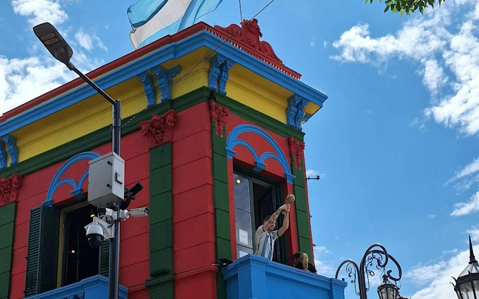 Colorful building in La Boca, Buenos Aires, with a figure holding a trophy on a balcony.