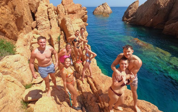 Group enjoying rocky cliffs at Cala del Molí, Costa Brava, Spain.