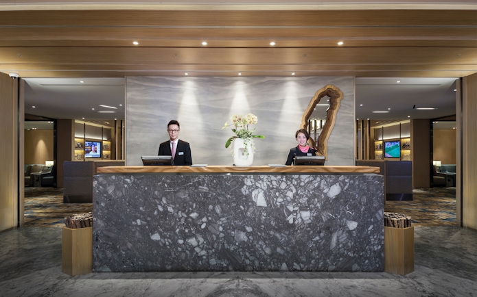 Reception desk at Plaza Premium Lounge, Zone D, Taipei, Taiwan with staff ready to assist.