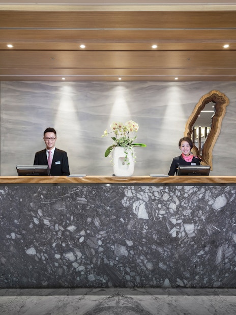 Reception desk at Plaza Premium Lounge, Zone D, Taipei, Taiwan with staff ready to assist.