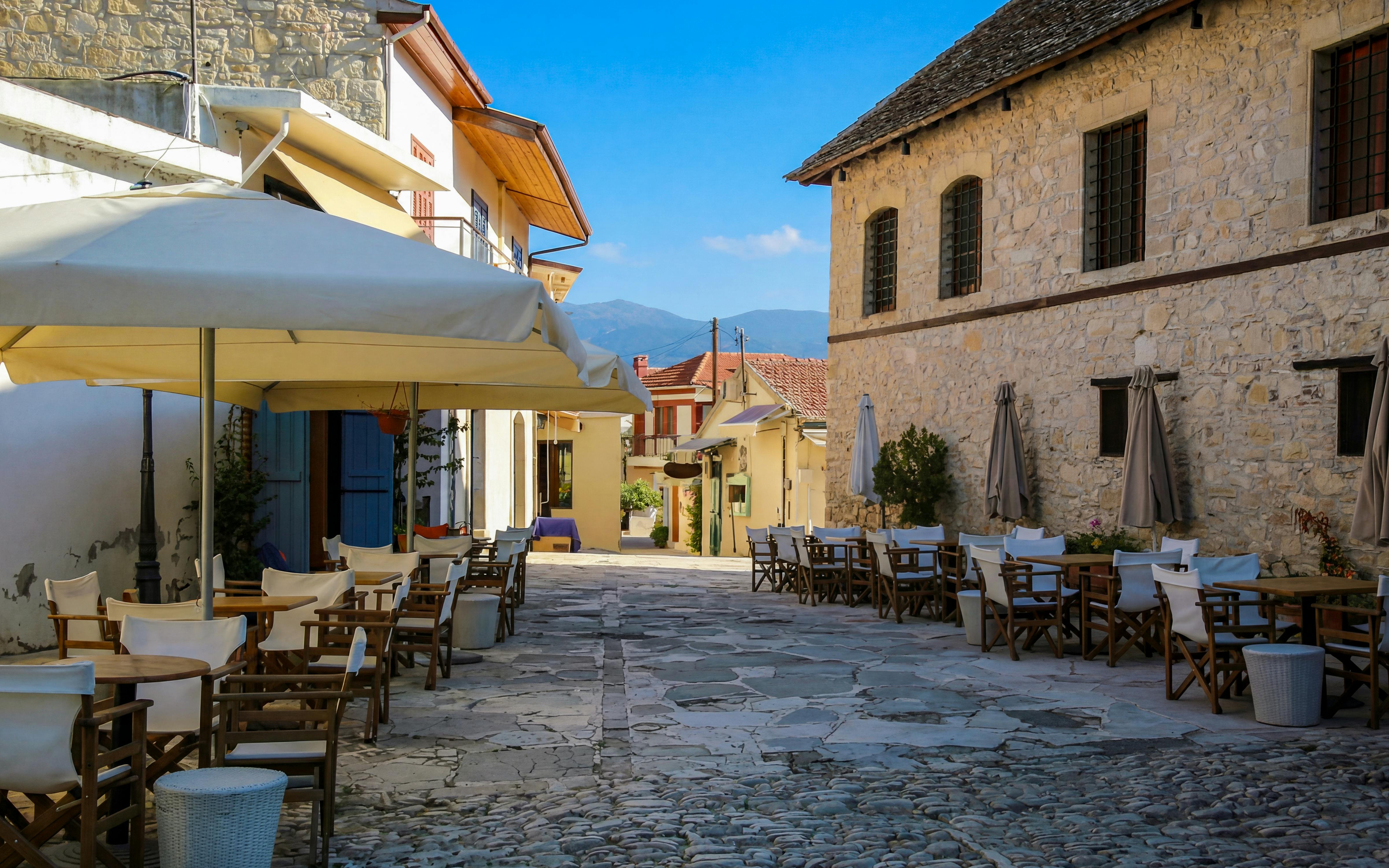 Outdoor cafe seating in a cobblestone street in Omodos village, Troodos Mountains, Cyprus.