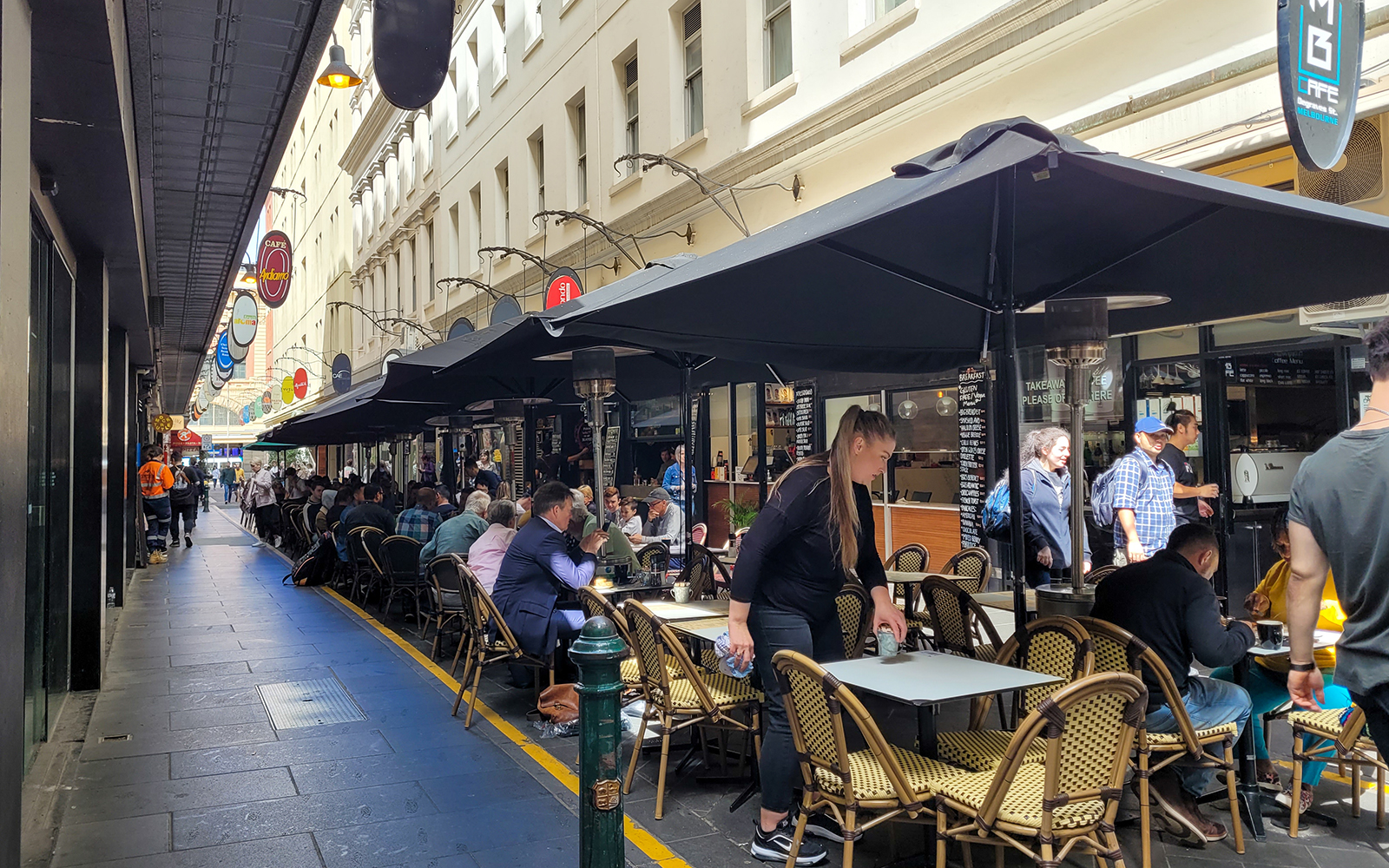 Outdoor café seating in a bustling Melbourne laneway during the Essential Melbourne Walking Tour.