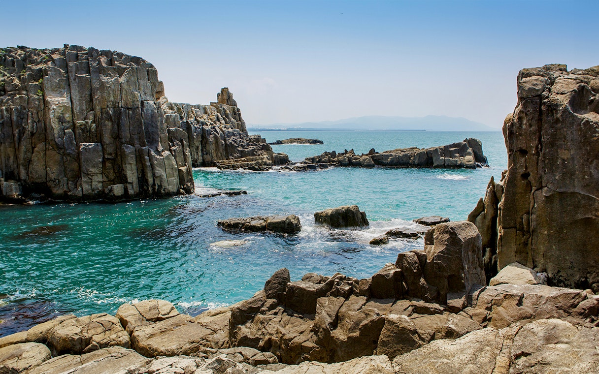 Rocky coastline of Tojinbo Cliffs in Hokuriku, Japan, with blue ocean waves.