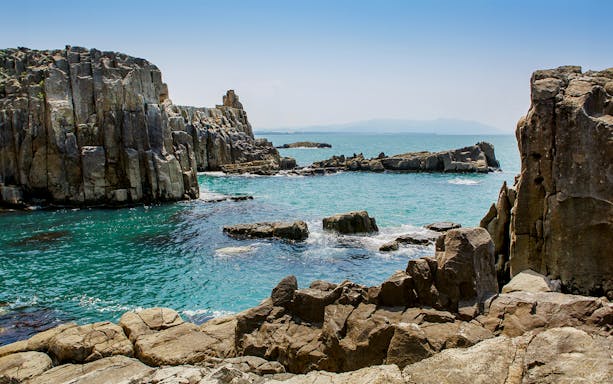 Rocky coastline of Tojinbo Cliffs in Hokuriku, Japan, with blue ocean waves.