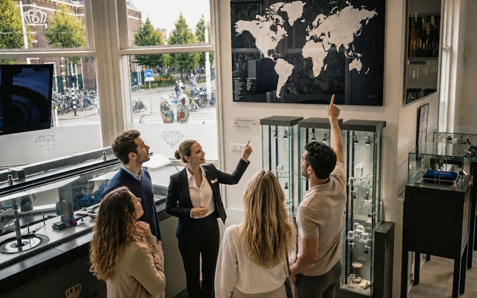 Group touring Royal Coster Diamonds showroom with world map display.
