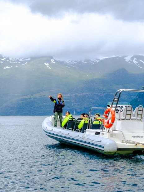 RIB boat with tourists on Geiranger Fjord safari, surrounded by mountains.