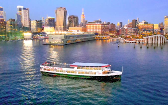 Circle Line cruise boat on Hudson River with New York City skyline at dusk.