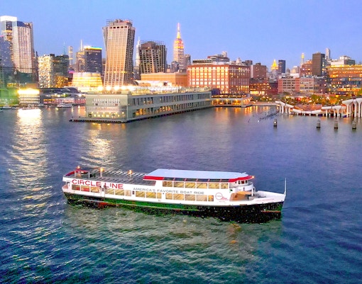 Circle Line cruise boat on Hudson River with New York City skyline at dusk.