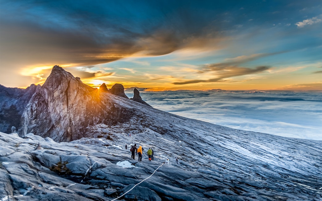 Hikers ascending Mount Kinabalu summit at sunrise, Malaysia.