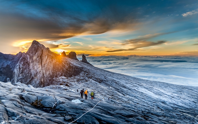 Hikers ascending Mount Kinabalu summit at sunrise, Malaysia.