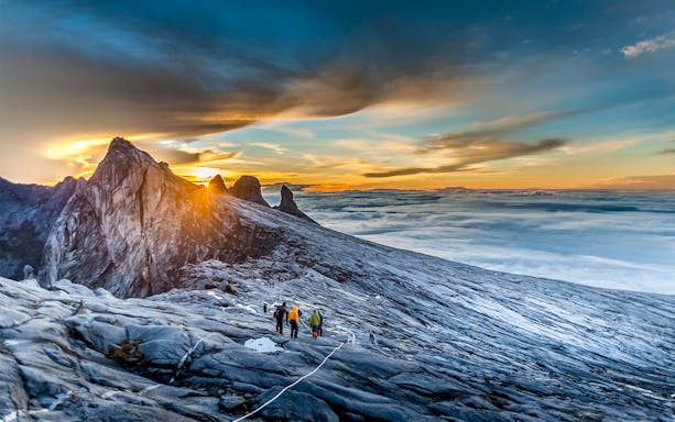 Hikers ascending Mount Kinabalu summit at sunrise, Malaysia.