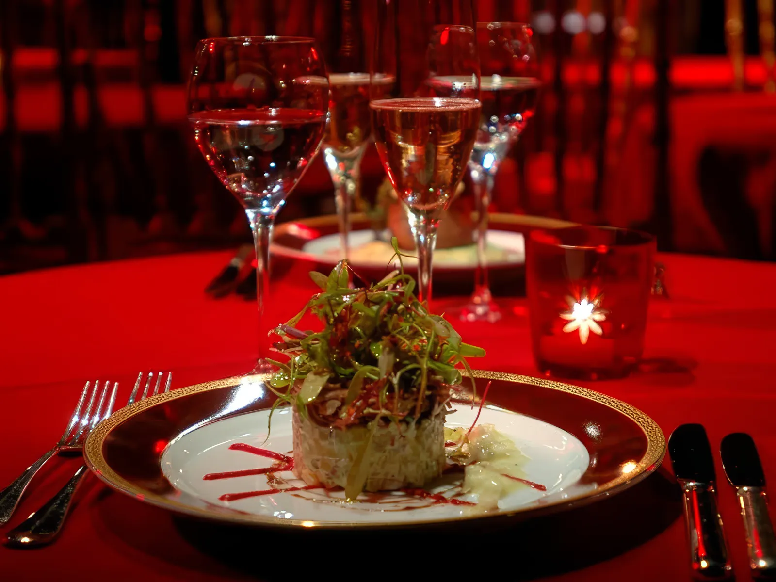 Elegant dinner setting at Rojo Tango Show with gourmet dish and wine glasses.