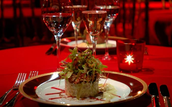 Elegant dinner setting at Rojo Tango Show with gourmet dish and wine glasses.